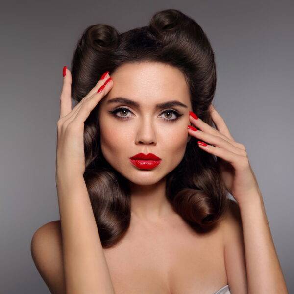 Pin up girl with red lips makeup, manicure nails and retro curls hair